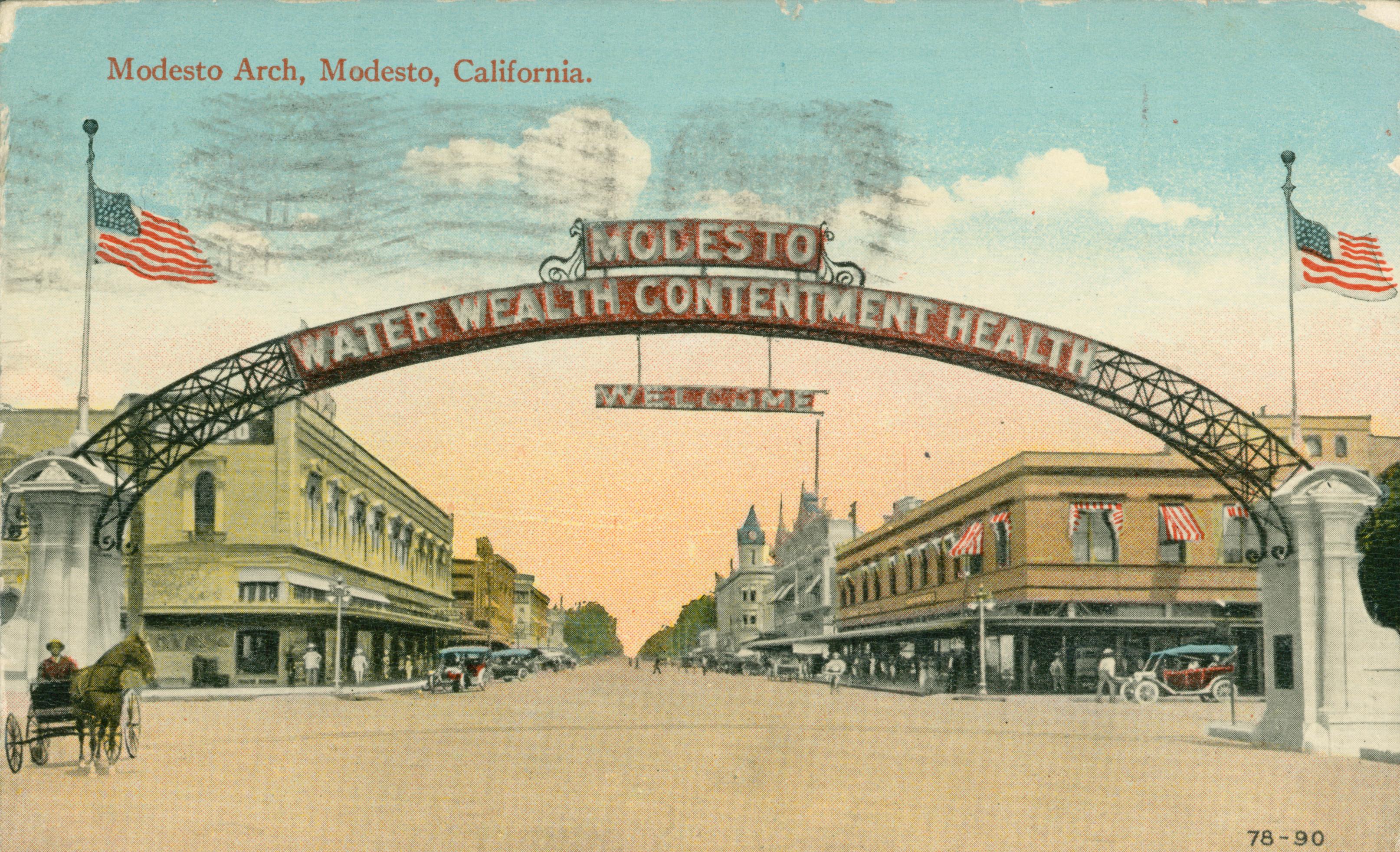 Shows the Modesto arch leading to a street lined with buildings